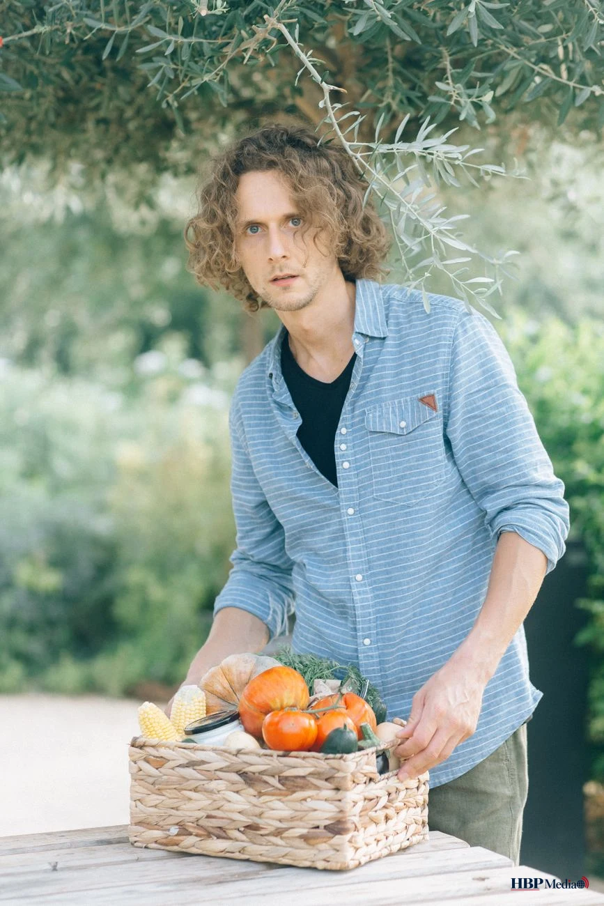man holding a woven basket full of vegetables