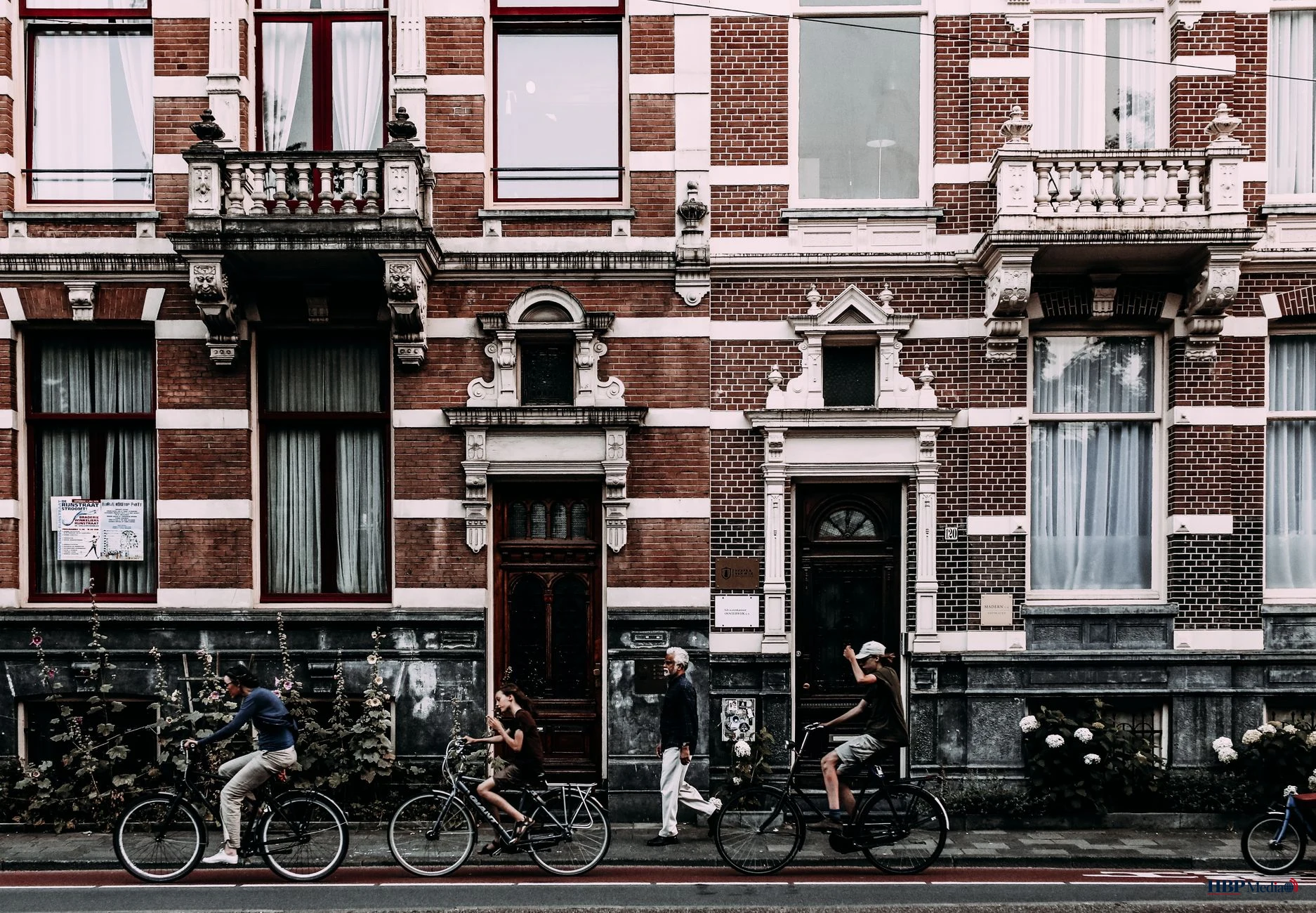 cyclists riding along old building