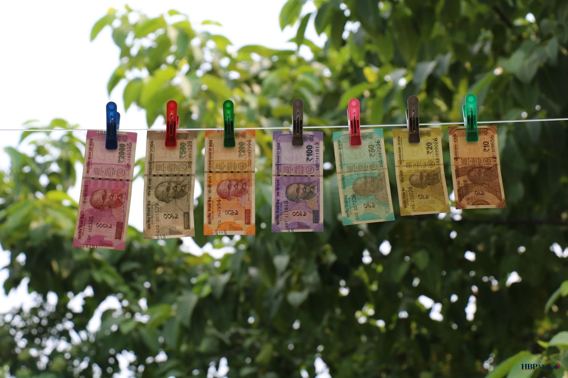 seven indian rupee banknotes hanging from clothesline on clothes pegs