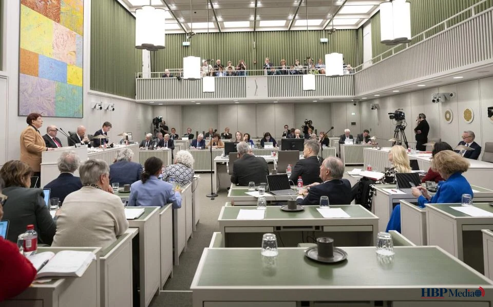 Voorzittershamer op een tafel met een kopie van de Nederlandse Grondwet, symbool voor politieke hervorming en de discussie over het afschaffen van de Eerste Kamer.