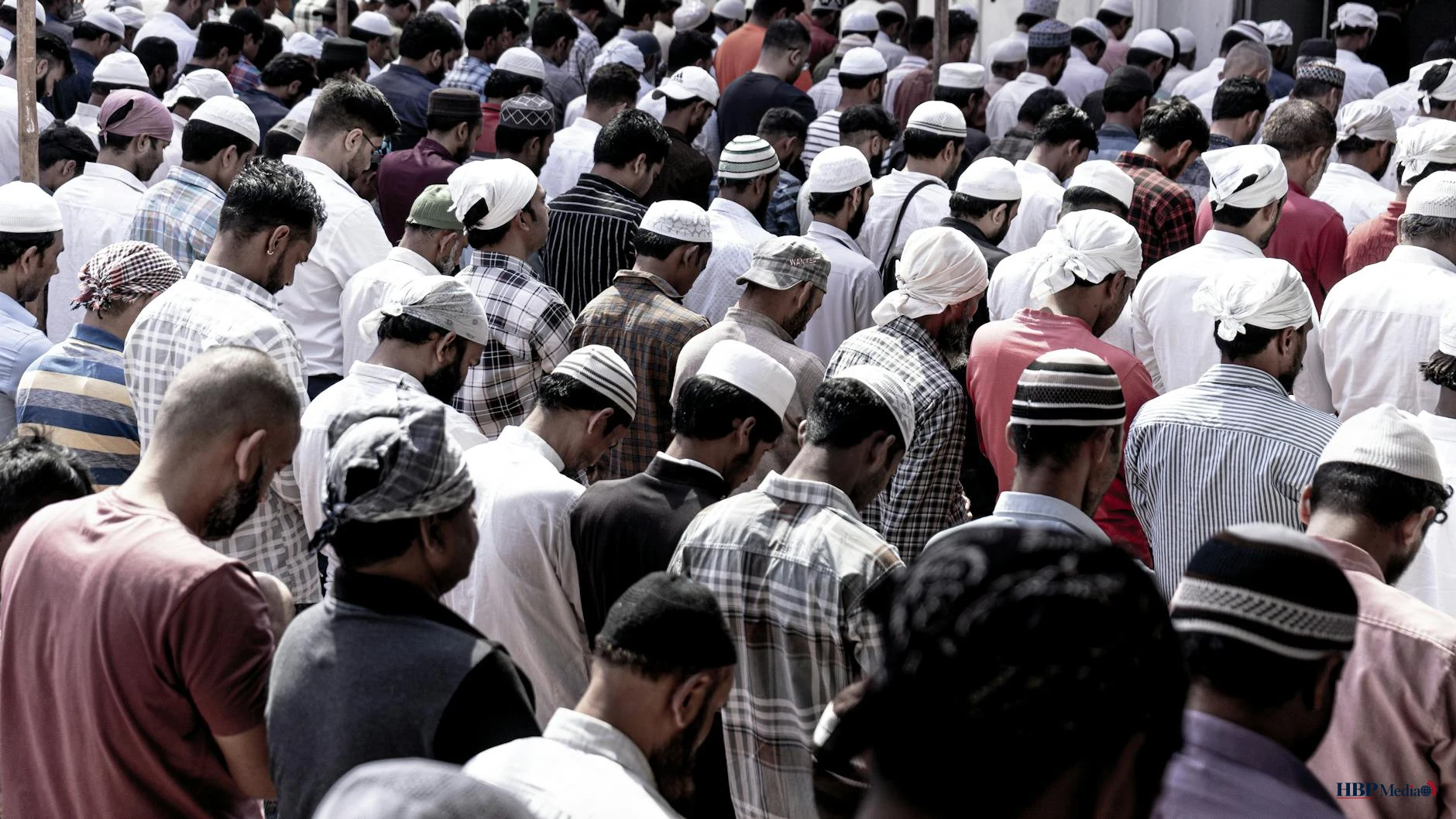 large group of men praying in outdoor setting