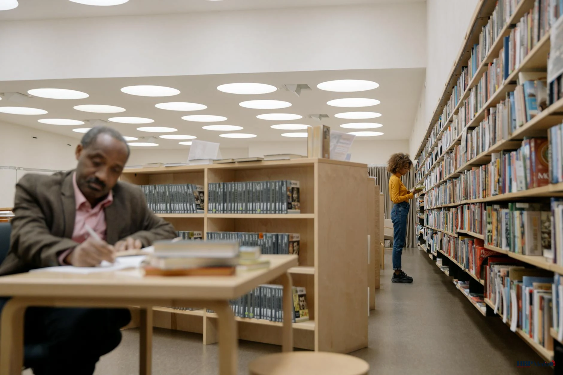 Interieur van een moderne openbare bibliotheek met bezoekers en gevulde boekenkasten.
