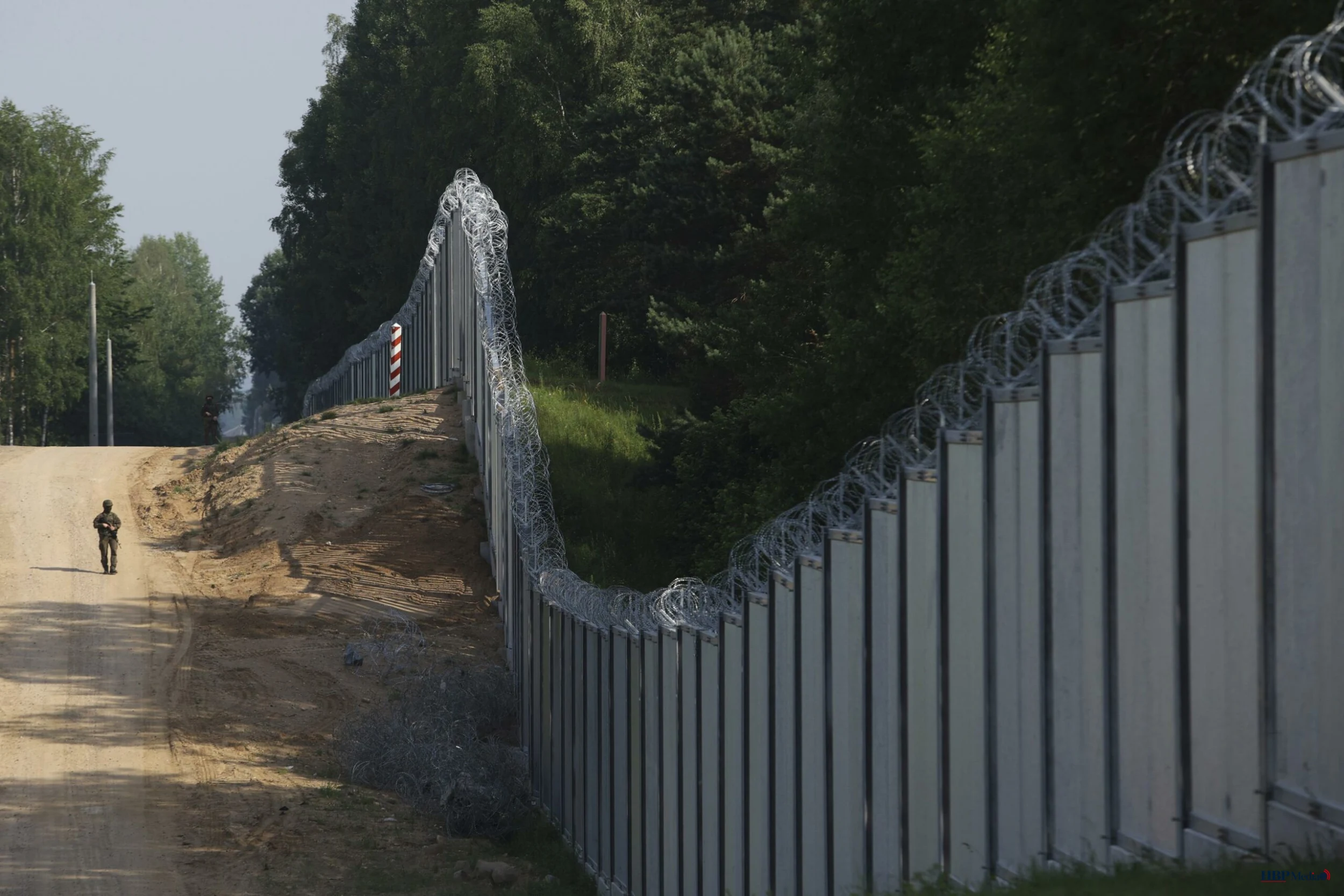 Grensgebied tussen Wit-Rusland en Polen met grenshekken en bosgebied.