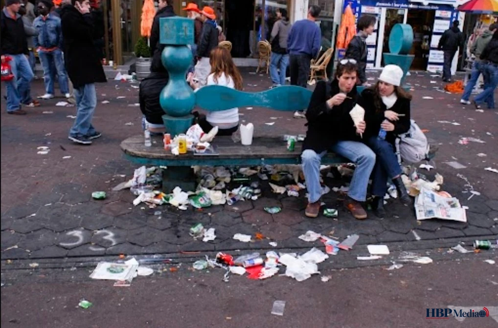 Afvalzakken en vuilnis naast volle containers in een straat na Koningsdag