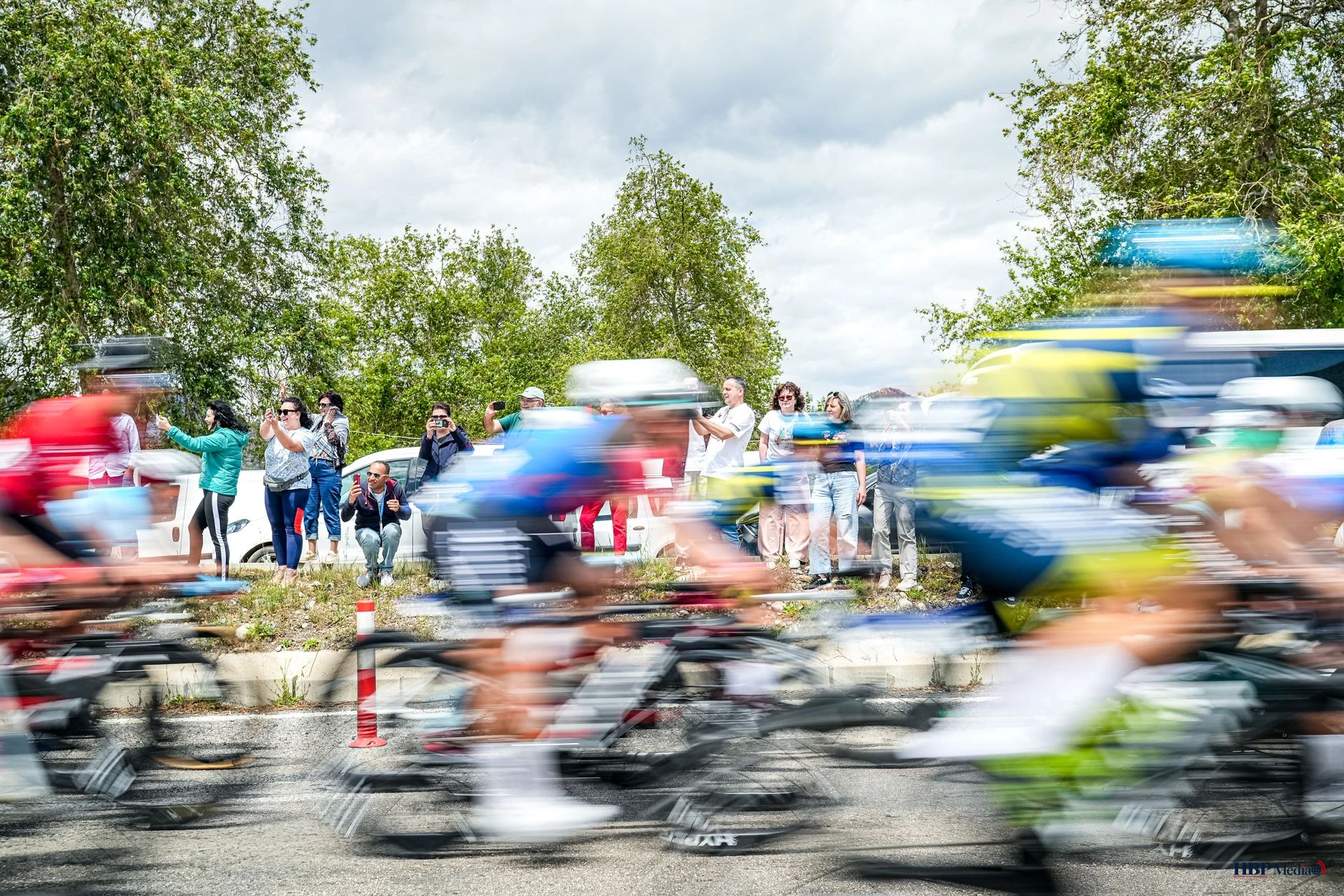 Een peloton wielrenners fietst onder een stralende zon tijdens de Tour de France.
