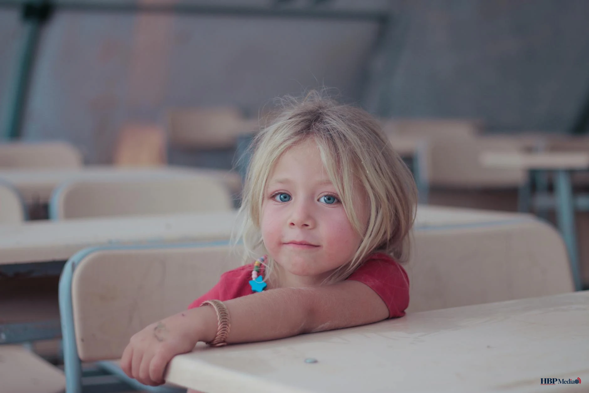 little girl in pink shirt leaning on a table