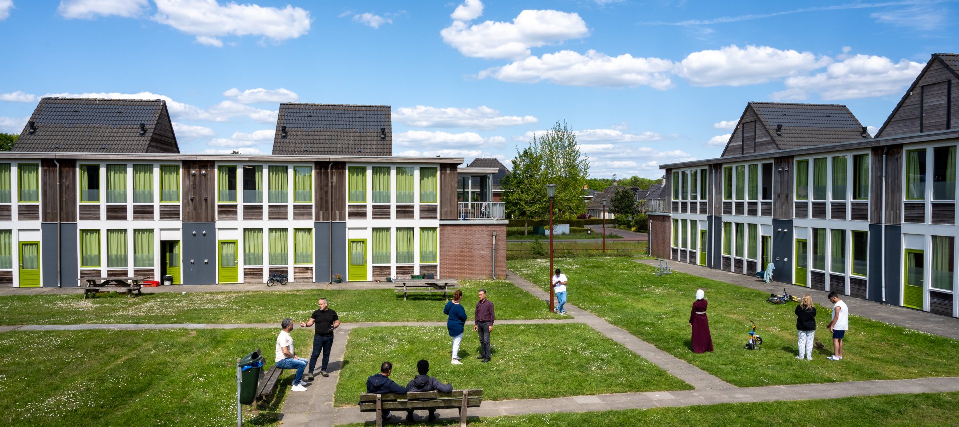 Vrijwilligers helpen nieuwkomers in een AZC, symbool voor solidariteit na het anti-AZC-lied in Nederland.