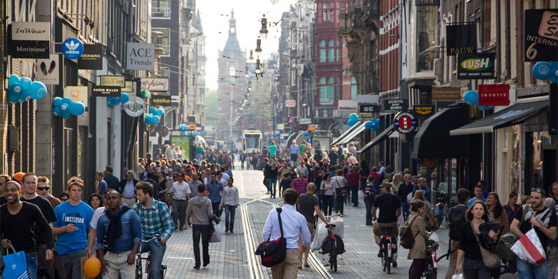 Winkelstraat met herfstcollectie en winkelende mensen — lagere kledingprijzen zorgen voor dalende inflatie in Nederland.
