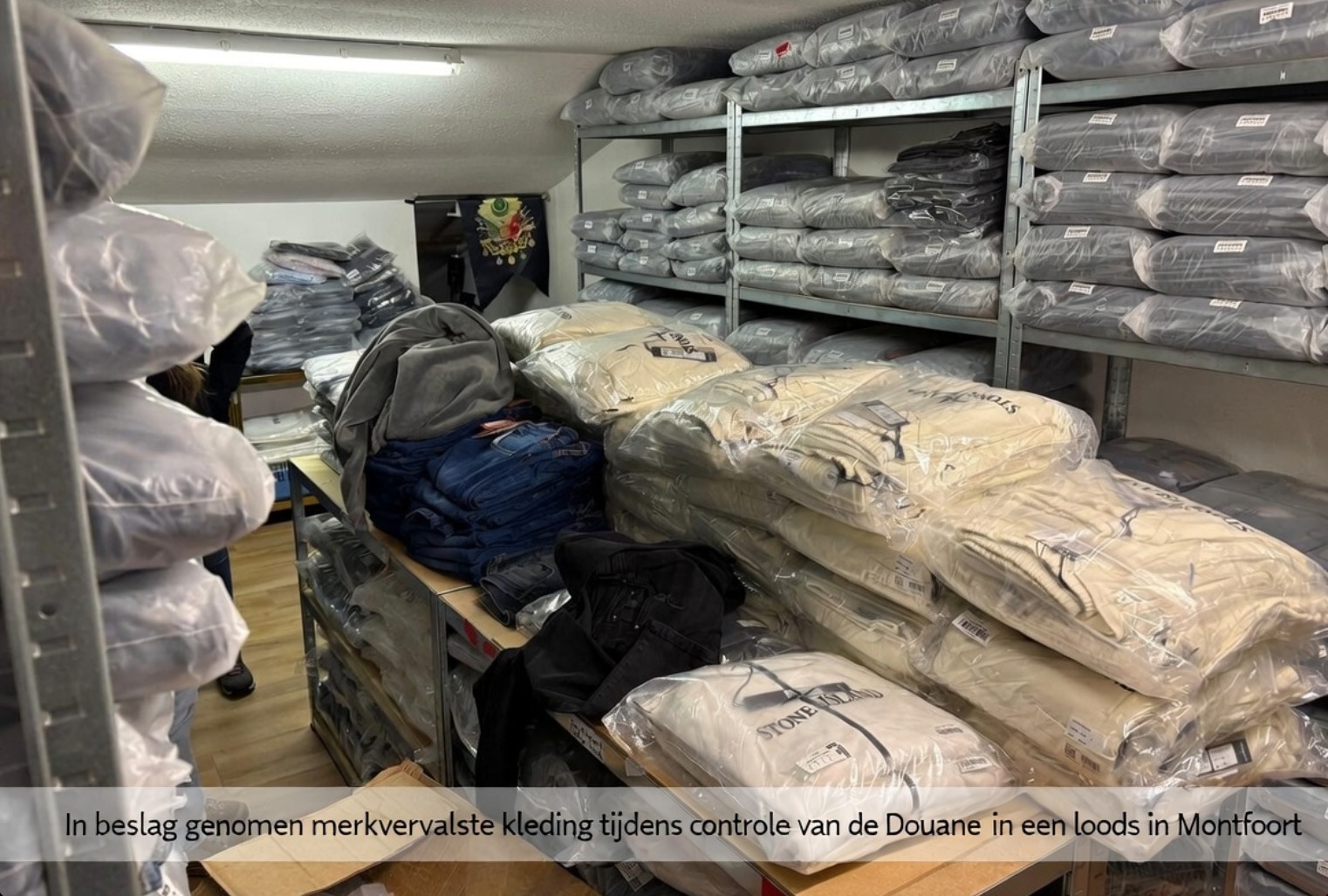 In beslag genomen merkvervalste kleding tijdens controle van de Douane in een loods in Montfoort